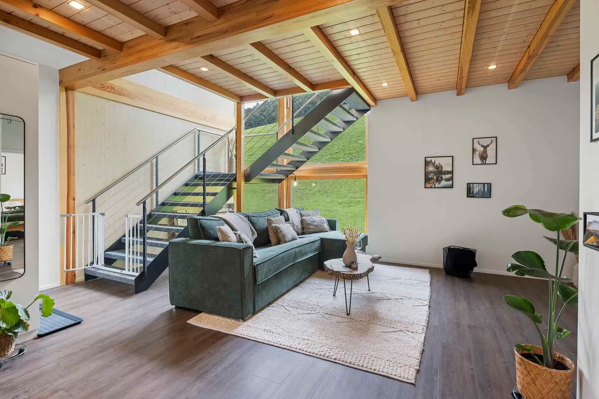 Wohnzimmer mit grünem Sofa und offener Treppe zum Galeriegeschoss